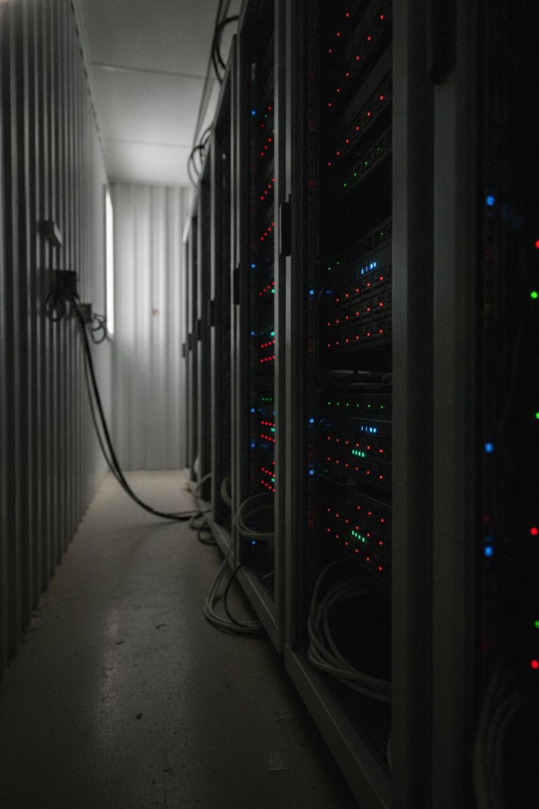 Server rack with blinking LEDs in dark data center, illustrating observability in autonomous AI assistant vs copilot comparison